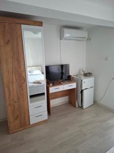 a room with a bed and a desk with a television at Guest House Damyanov in Ravda