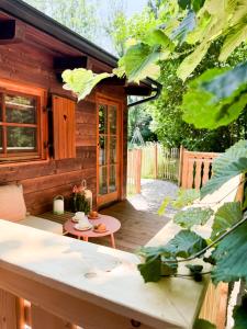 a small wooden cabin with a deck with a table at Arriach Apartments in Arriach