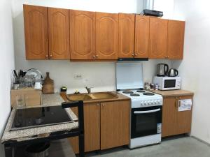 a kitchen with wooden cabinets and a stove and a sink at Hostel Casa Mia SR in Sarandë