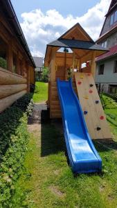 einen Spielplatz mit Rutsche neben einem Gebäude in der Unterkunft Pokoje Gościnne Staszelówka in Małe Ciche