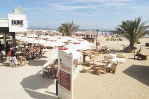 un grupo de mesas y sillas con sombrillas en una playa en Apho Apartment Hotel, en Rímini