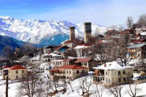 una città nella neve con montagne sullo sfondo di Guest House Lemsia a Mestia