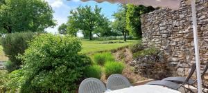 un muro in pietra con tavolo e sedie in giardino di La Grange de Rocamadour a Rocamadour