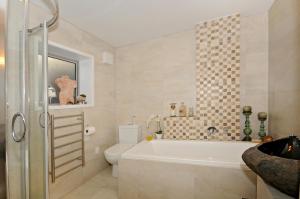 a bathroom with a tub and a toilet and a sink at Kapiti Waves in Pukerua Bay