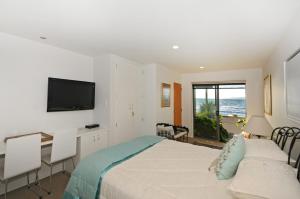 a bedroom with a bed and a desk and a television at Kapiti Waves in Pukerua Bay