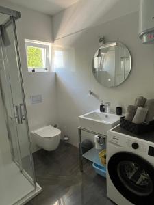 a bathroom with a sink and a washing machine at Apartmani Foresta in Kras +43 photos