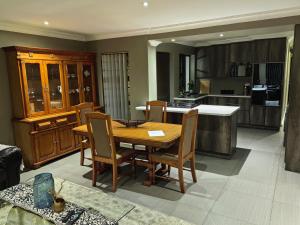 a kitchen and dining room with a wooden table and chairs at The Close in Gqeberha