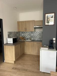 a kitchen with wooden cabinets and a white refrigerator at Chez Noémie in Saintes