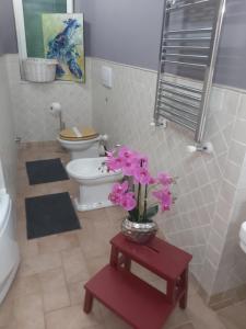 a bathroom with a toilet and a vase of flowers on a table at La Bandiera Blu in La Spezia +52 photos