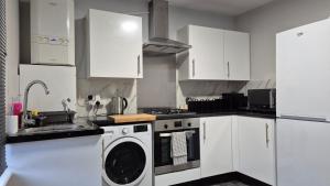 a kitchen with white cabinets and a washing machine at Modern Stylish Flat - allocated parking! in Reading