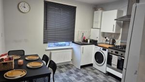 a kitchen with a table and a stove and a dishwasher at Modern Stylish Flat - allocated parking! in Reading +9 photos