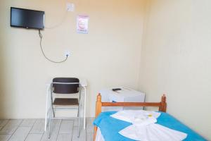 a room with a bed with a tv and a chair at Hotel Naturalis in Paranaguá
