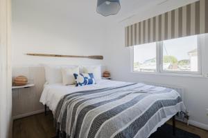 1 dormitorio blanco con 1 cama con manta azul y blanca en Restful Riverside Retreat, en Christchurch