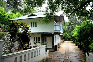 a white house with a fence in front of it at Spring Muunnar, Munnar in Munnar