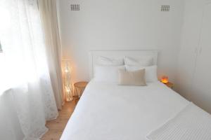 a white bed with white pillows in a bedroom at Coastal Family & Pet friendly home in Ettalong Beach in Ettalong Beach