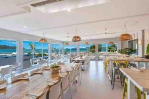 a dining room with tables and chairs and the ocean at Coastal Family & Pet friendly home in Ettalong Beach in Ettalong Beach