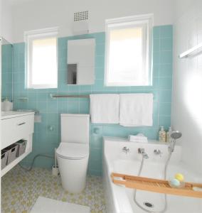 a bathroom with a tub and a toilet and a sink at Coastal Family & Pet friendly home in Ettalong Beach in Ettalong Beach +20 photos