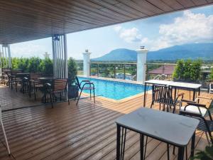 a deck with tables and chairs and a swimming pool at Ranisa Kampot in Kampot
