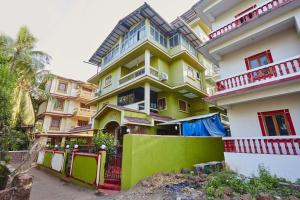 une maison jaune et blanche avec une clôture devant elle dans l'établissement Saikunj Holiday Homes, à Candolim