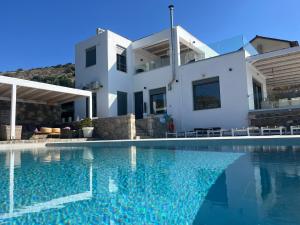 a villa with a swimming pool in front of a house at Villa Estée, luxury villa with private infinity pool and jacuzzi in Elounda