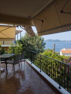 a balcony with a table and chairs and a view of the ocean at Palio Luxury Apartment in Paleo Tsifliki