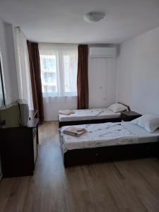 a room with three beds in it with a television at Guest House Damyanov in Ravda