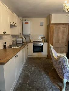 una cucina con mobili bianchi e un lavandino di Sycamore Cottage - Lake District Hiking & Rivers a Cockermouth
