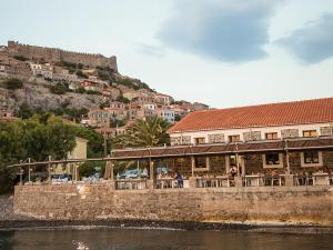 a restaurant on the side of a river with a mountain at Olive Press Hotel in Mythimna