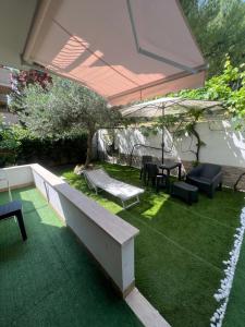 a patio with a bench and an umbrella and grass at B&B Giordano in Porto SantʼElpidio