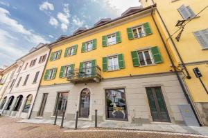 阿罗纳Arona Palace的黄色的建筑,设有绿色的白色窗户