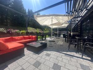 patio z kanapą, stołami i parasolem w obiekcie Hotel Jakuszyce Sport & Spa w Szklarskiej Porębie