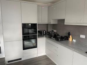 a kitchen with white cabinets and black appliances at Brand New High Spec House with Parking & Wi-Fi By Home Away From Home - B in Newcastle under Lyme +5 photos
