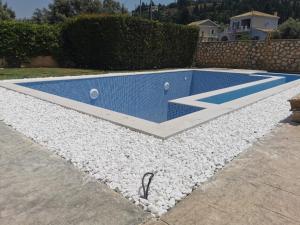 a swimming pool with white rocks around it at Villa Adelais in Tsoukaladhes