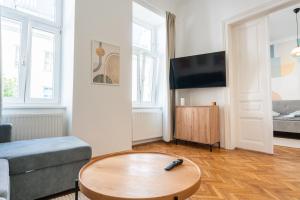 a living room with a tv and a table at Premium Suites Vienna - City Stay in Vienna