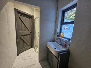 a bathroom with a sink and a window and a door at The Gallery Cottage in Castledawson +36 photos