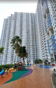 a large apartment building with a playground in front of it at Anderson pakuwon 2 Bedroom 6 people stay in Surabaya