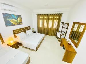 Un dormitorio con dos camas y una mesa y una silla. en The Cottage Ambuluwawa, en Gampola