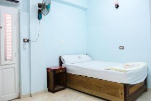 a small room with a bed and a clock on the wall at Grand M in ‘Izbat aş Şafīḩ