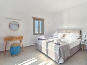 a white bedroom with a bed and a table at Ilios 2 Apartment Paros Naousa in Naousa +9 photos