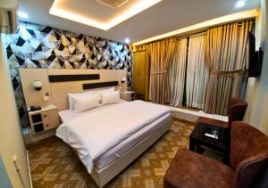 a bedroom with a large white bed and a chair at New Crown Palace Hotel in Islamabad