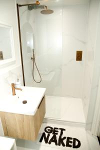 a bathroom with a white sink and a shower with a get wanted sign at Jazreal Luxury Apartment - Leeds City Centre in Leeds +11 photos