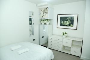 a white bedroom with a bed and a mirror at Jazreal Luxury Apartment - Leeds City Centre in Leeds