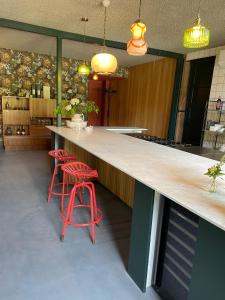 een keuken met een groot aanrecht met rode krukken bij B&B Boudevino in Lekkerkerk
