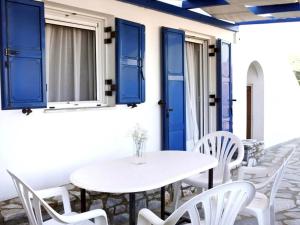 a white table and chairs on a porch with blue shutters at Kalliopi's Aegean View in Episkopíon