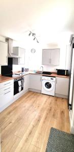 a kitchen with white cabinets and a wooden floor at Stunning 2 Bed House, Cleethorpes - Contractors Welcome! in Cleethorpes