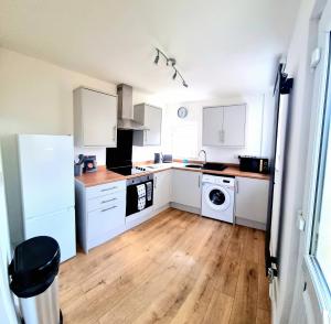 a kitchen with white cabinets and a wooden floor at Stunning 2 Bed House, Cleethorpes - Contractors Welcome! in Cleethorpes