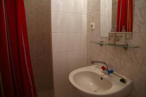 a bathroom with a sink and a red shower curtain at Apartmány Adriana in Veľký Meder