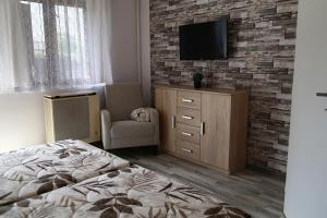 a bedroom with a bed and a tv on a brick wall at Apartmány Adriana in Veľký Meder