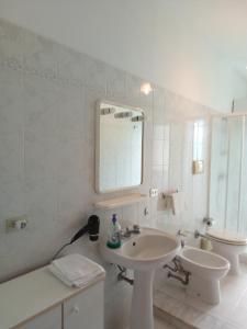 a white bathroom with a sink and a toilet at Miramare Oliveri in Oliveri +15 photos