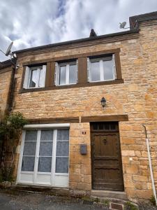 Petite maison au pied du château في Salignac Eyvigues: منزل من الطوب مع باب بني ونوافذ